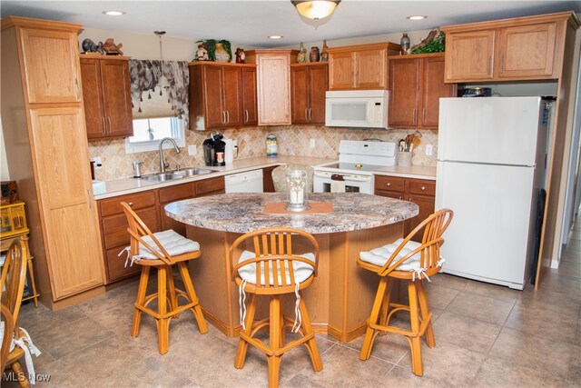 kitchen featuring tasteful backsplash, light countertops, a kitchen island, a sink, and white appliances