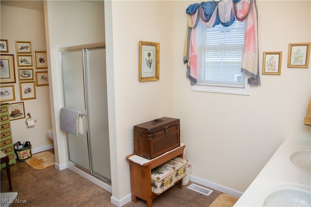 bathroom featuring tile patterned flooring, a shower with door, vanity, and toilet