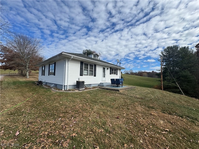 view of front of home with a front lawn, a patio, and central AC