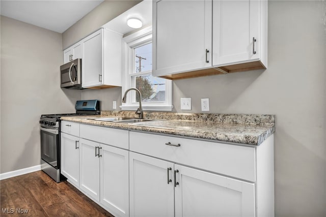 kitchen with dark hardwood / wood-style floors, white cabinetry, sink, and appliances with stainless steel finishes