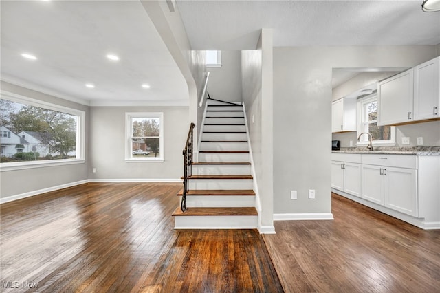 stairway featuring sink, ornamental molding, and hardwood / wood-style flooring