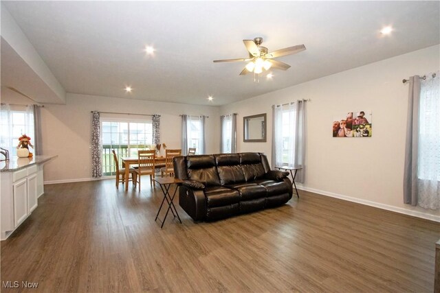 living room with dark hardwood / wood-style flooring and ceiling fan