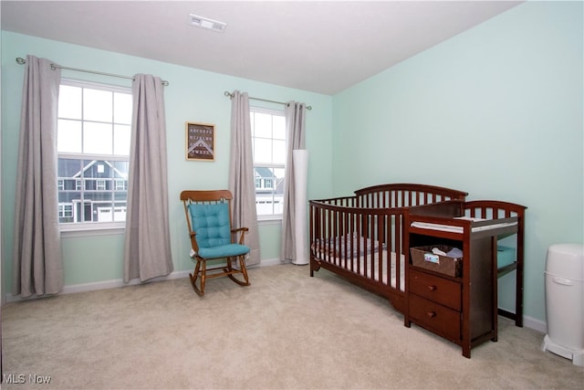 bedroom featuring a crib and light colored carpet