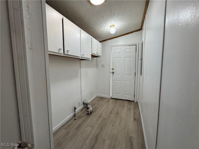 clothes washing area featuring a textured ceiling, light hardwood / wood-style floors, and crown molding