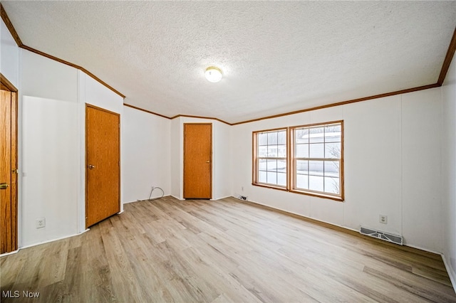 unfurnished bedroom featuring crown molding, light hardwood / wood-style flooring, and a textured ceiling