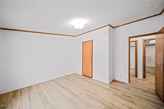 spare room featuring ornamental molding, a textured ceiling, and light hardwood / wood-style floors