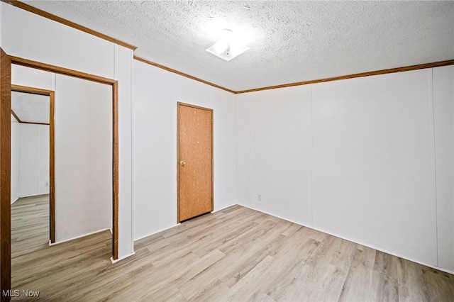 unfurnished room featuring crown molding, a textured ceiling, and light hardwood / wood-style floors