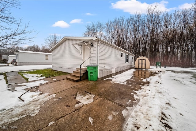 snow covered property featuring a storage shed