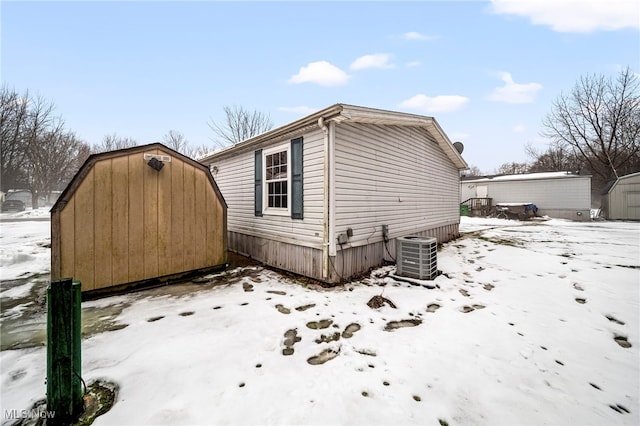 snow covered property featuring a storage shed and central air condition unit