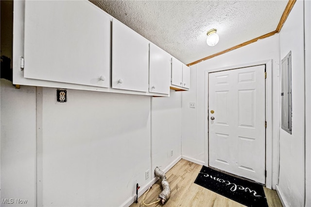 laundry area featuring cabinets, light wood-type flooring, and a textured ceiling