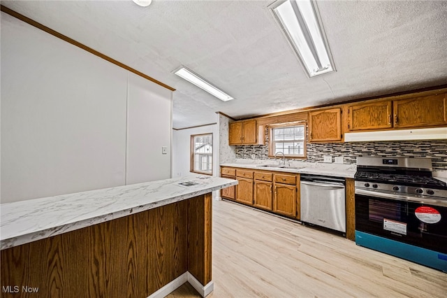 kitchen with sink, light hardwood / wood-style flooring, appliances with stainless steel finishes, a textured ceiling, and decorative backsplash