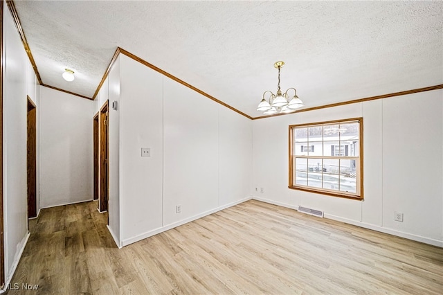 empty room featuring ornamental molding, light hardwood / wood-style floors, and a textured ceiling