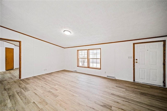 interior space featuring crown molding, a textured ceiling, and light wood-type flooring