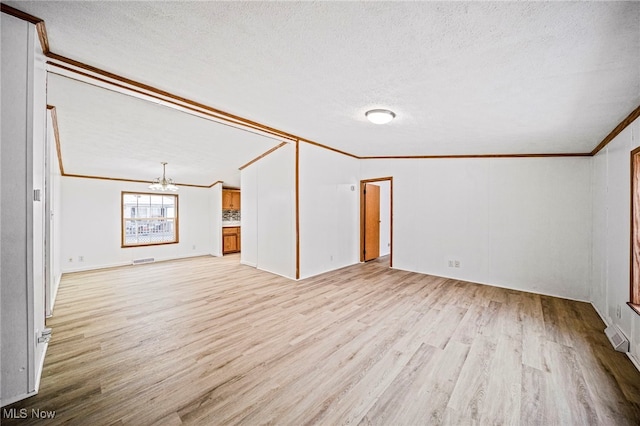 interior space featuring an inviting chandelier, ornamental molding, light hardwood / wood-style floors, and a textured ceiling