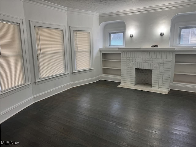 unfurnished living room featuring dark hardwood / wood-style flooring, ornamental molding, a textured ceiling, and a brick fireplace