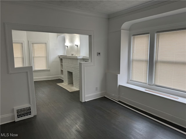 unfurnished living room with a fireplace, a textured ceiling, dark hardwood / wood-style flooring, and crown molding