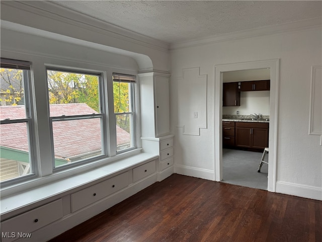 empty room featuring ornamental molding, a textured ceiling, dark hardwood / wood-style floors, and a healthy amount of sunlight