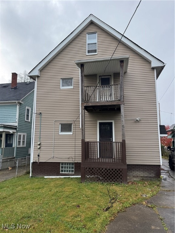 back of house featuring a balcony and a yard