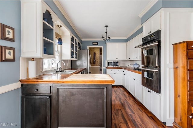 kitchen with white cabinetry, hanging light fixtures, stainless steel appliances, kitchen peninsula, and ornamental molding