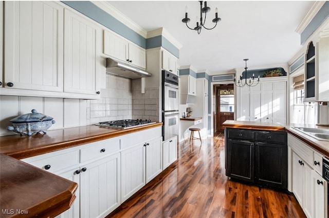 kitchen featuring stainless steel gas cooktop, dark wood-type flooring, decorative light fixtures, a chandelier, and white cabinetry