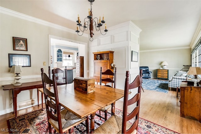 dining space featuring a chandelier, ornamental molding, a healthy amount of sunlight, and wood-type flooring