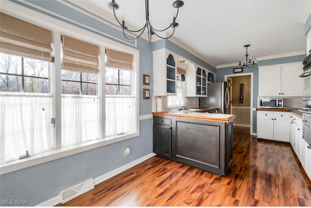 kitchen with a chandelier, wooden counters, a healthy amount of sunlight, and appliances with stainless steel finishes