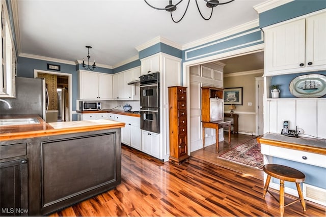 kitchen featuring wooden counters, appliances with stainless steel finishes, dark hardwood / wood-style flooring, a chandelier, and hanging light fixtures