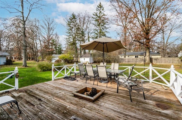 wooden terrace with a storage shed and a lawn