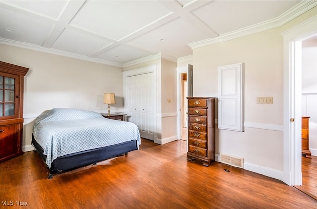 bedroom with a closet, wood-type flooring, coffered ceiling, and ornamental molding