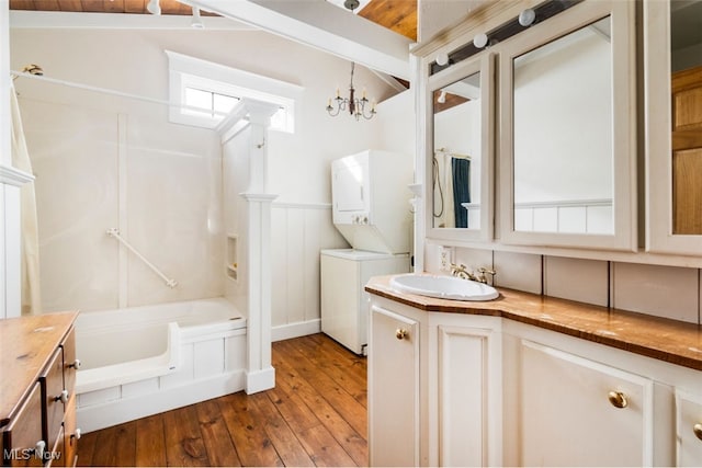 bathroom featuring vanity, an inviting chandelier, stacked washer and dryer, vaulted ceiling, and hardwood / wood-style flooring