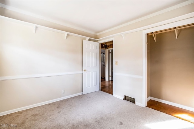 unfurnished bedroom with a closet, carpet floors, and ornamental molding