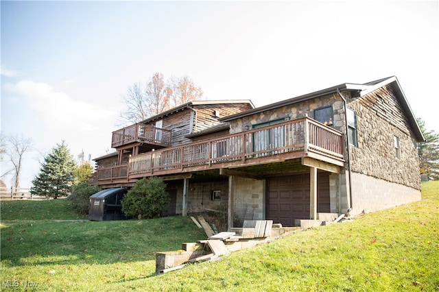 back of property featuring a yard, a garage, and a deck