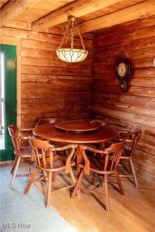 dining room featuring wood ceiling, rustic walls, wood-type flooring, and beam ceiling