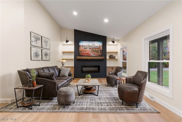 interior space featuring a large fireplace, hardwood / wood-style flooring, and lofted ceiling