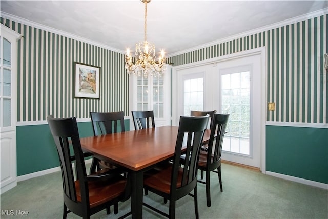 carpeted dining space with a chandelier and ornamental molding