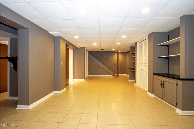 hall with a drop ceiling and light tile patterned flooring