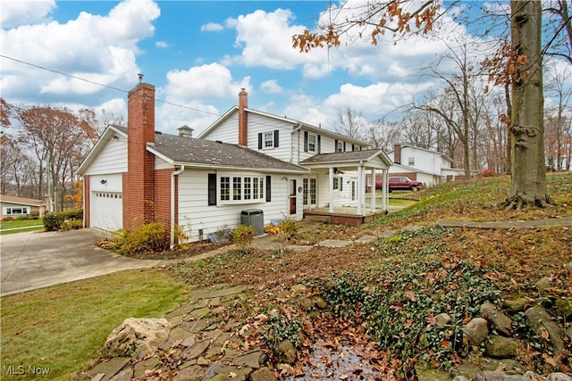 back of house featuring covered porch, central AC, and a garage