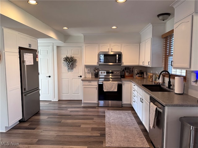 kitchen featuring white cabinetry, sink, dark wood-type flooring, stainless steel appliances, and decorative backsplash