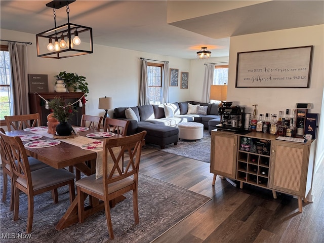 dining room with indoor bar, dark hardwood / wood-style floors, and an inviting chandelier