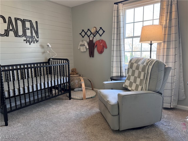 carpeted bedroom featuring a nursery area and wood walls