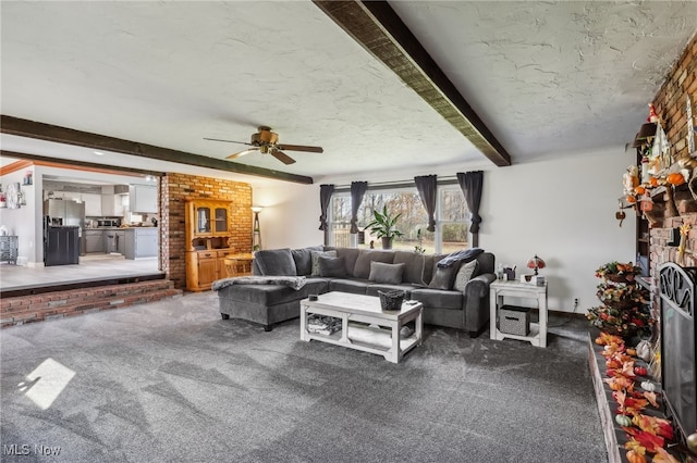 carpeted living room featuring ceiling fan, a fireplace, beamed ceiling, and a textured ceiling