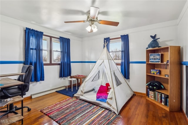 interior space featuring hardwood / wood-style flooring, baseboard heating, multiple windows, and ceiling fan