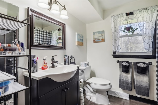 bathroom featuring hardwood / wood-style floors, vanity, toilet, and a notable chandelier