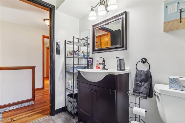 2500 Douglas Rd, Ashtabula, OH 44004 - half bath with vanity, toilet, a chandelier, wood finished floors, and baseboards