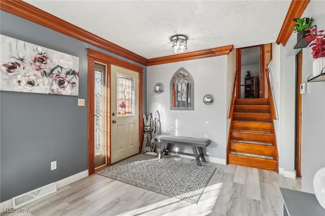 foyer entrance featuring crown molding, light hardwood / wood-style floors, and a textured ceiling