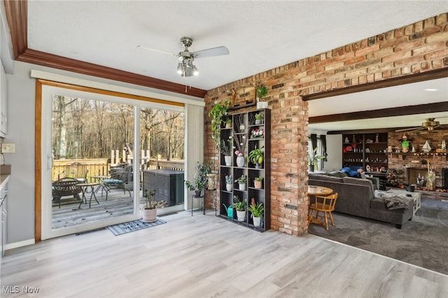 interior space with ceiling fan, brick wall, and light hardwood / wood-style flooring