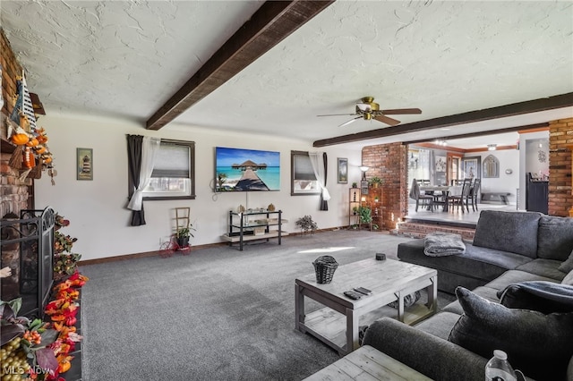 carpeted living room with beamed ceiling, ceiling fan, a fireplace, and a textured ceiling