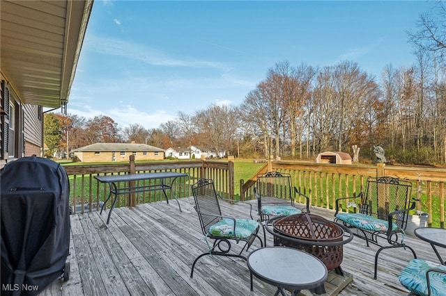 deck featuring a fire pit, area for grilling, and a lawn