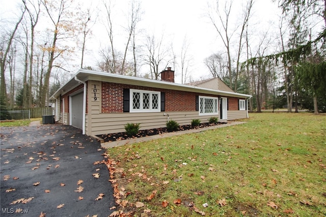 view of front of home featuring cooling unit, a front yard, and a garage