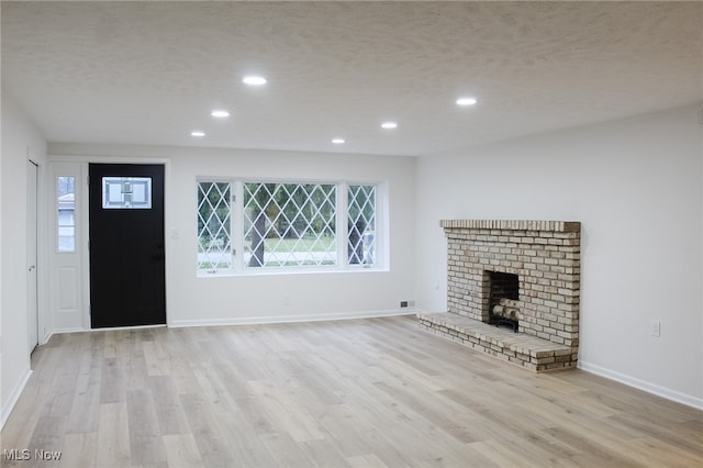 unfurnished living room with a textured ceiling, light hardwood / wood-style floors, and a fireplace